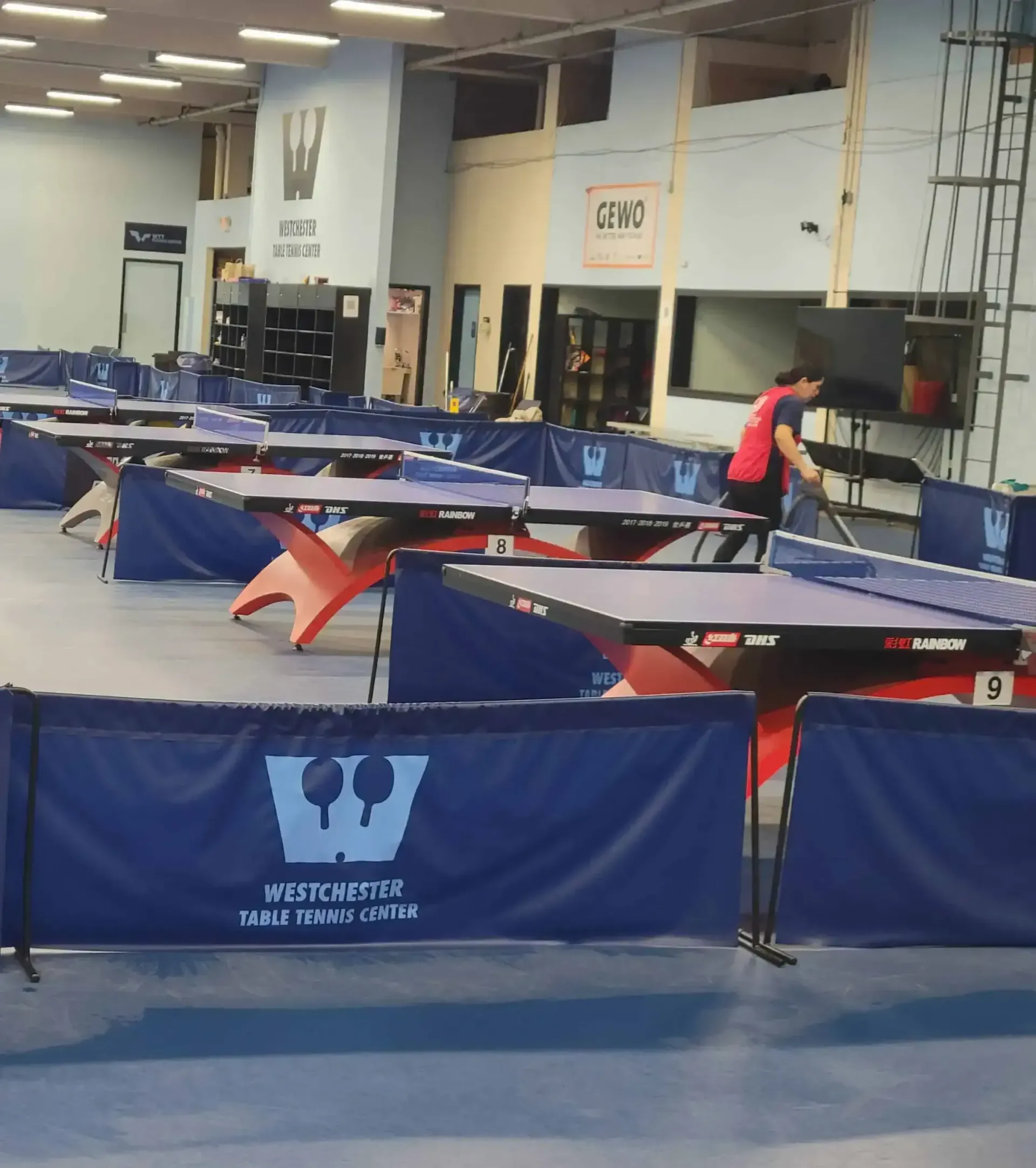A man in a red shirt is playing ping pong