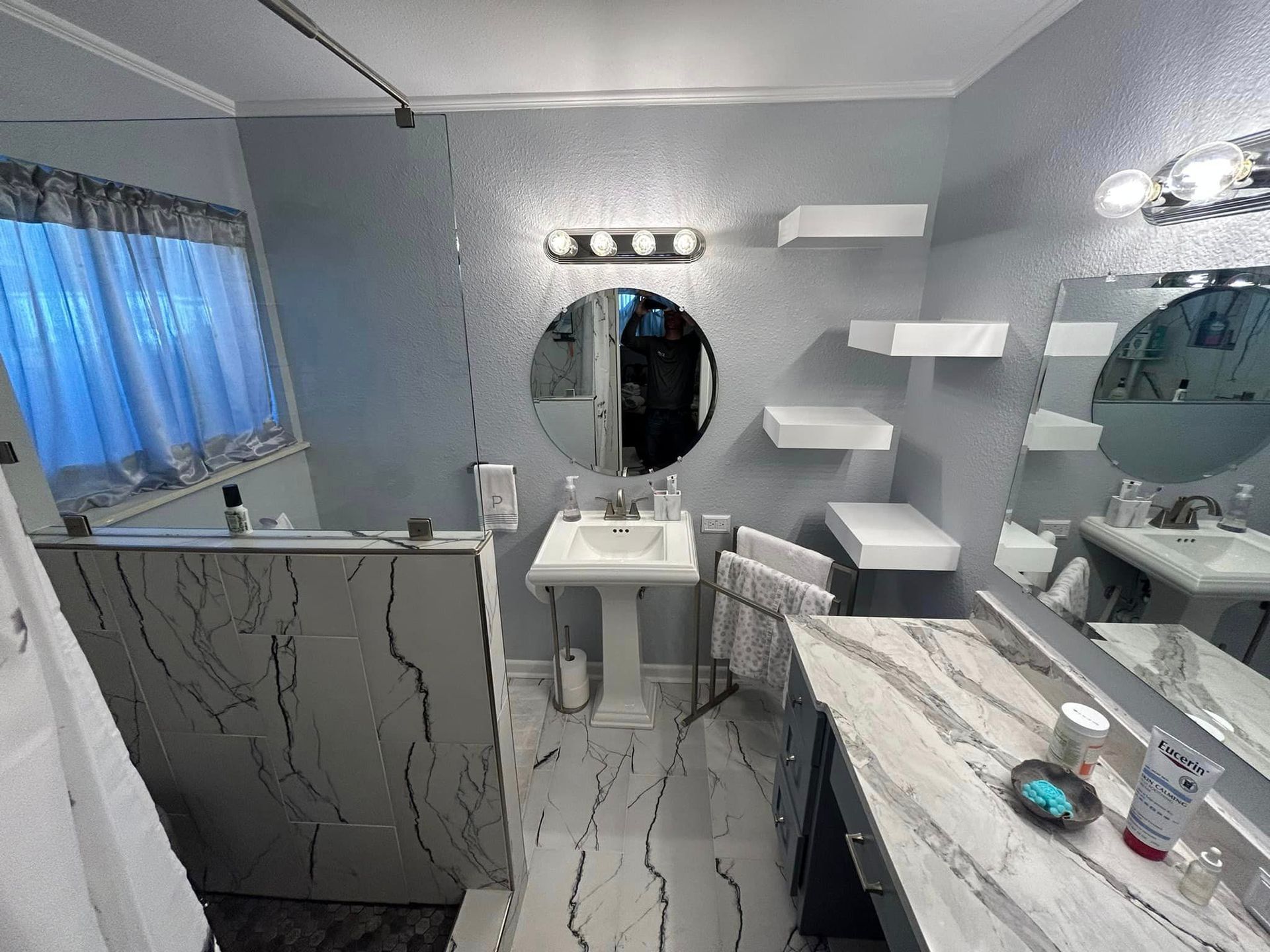 A bathroom with two sinks , a mirror , and a walk in shower.