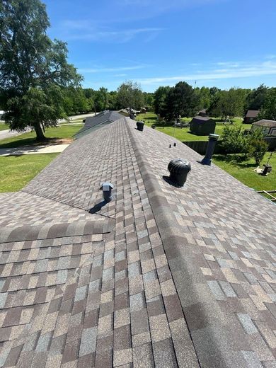 A roof with a lot of shingles on it and trees in the background.