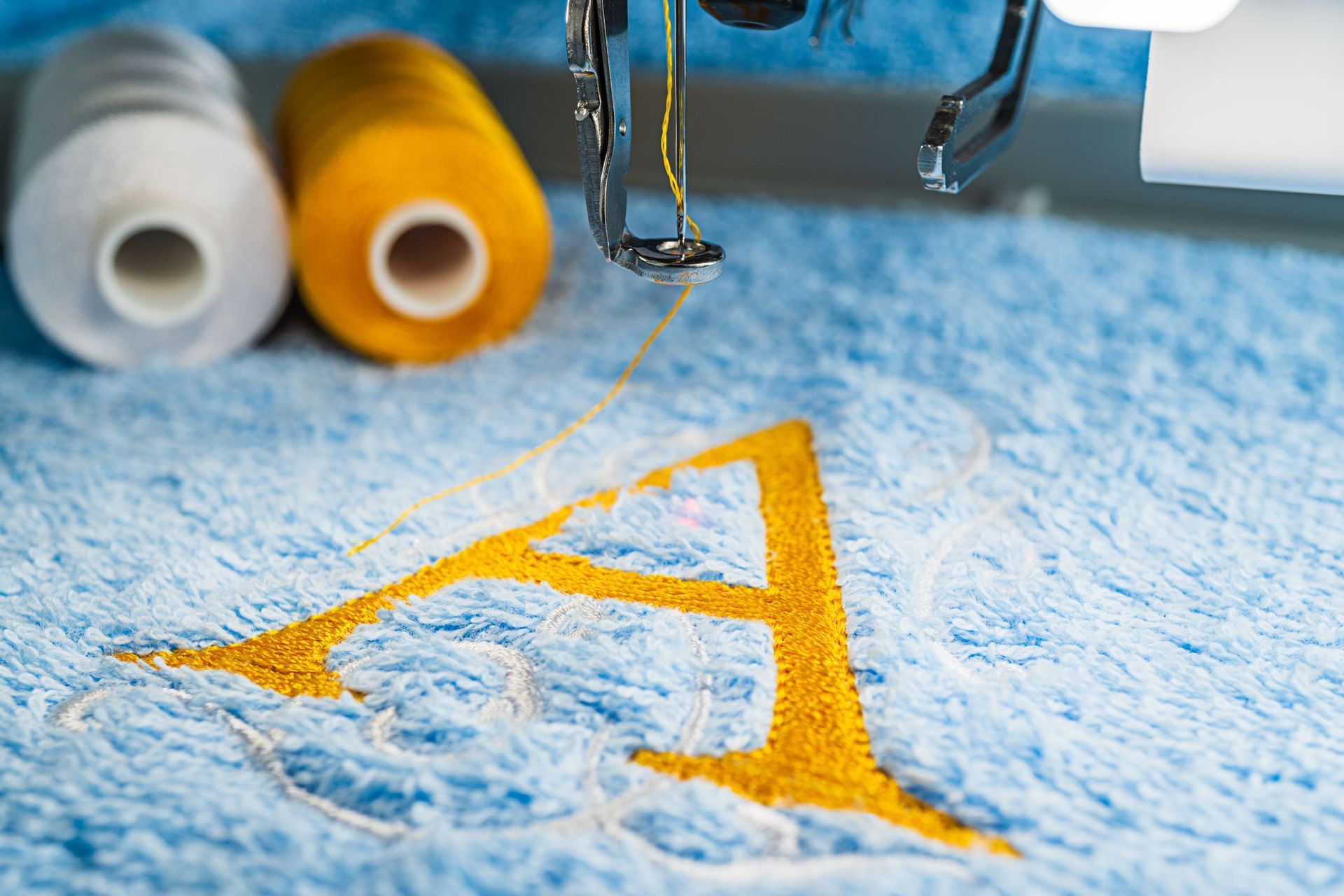 Embroidery machine stitching a yellow letter 