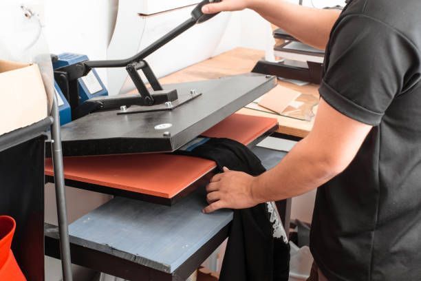Person using a heat press machine on a black t-shirt.