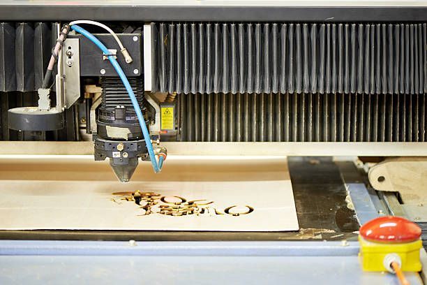 Laser cutter engraving a design on light-colored wood. Close-up view of the machine and the cutting process.