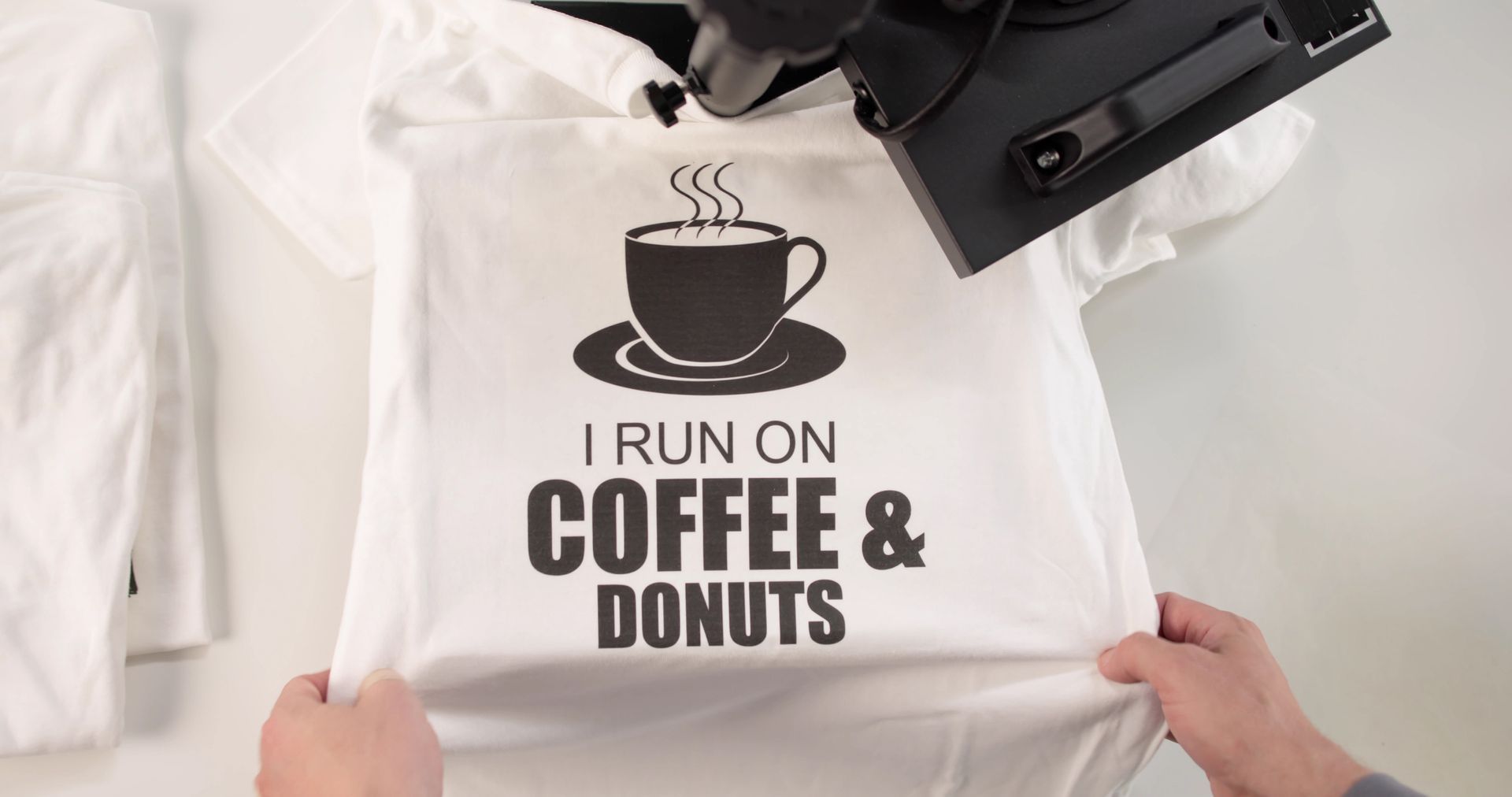 Hands packing folded white sweater into cardboard box filled with clothing.