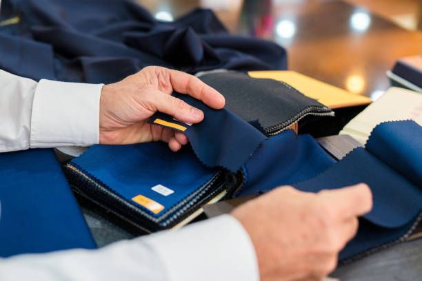 Hands holding and comparing blue fabric swatches.