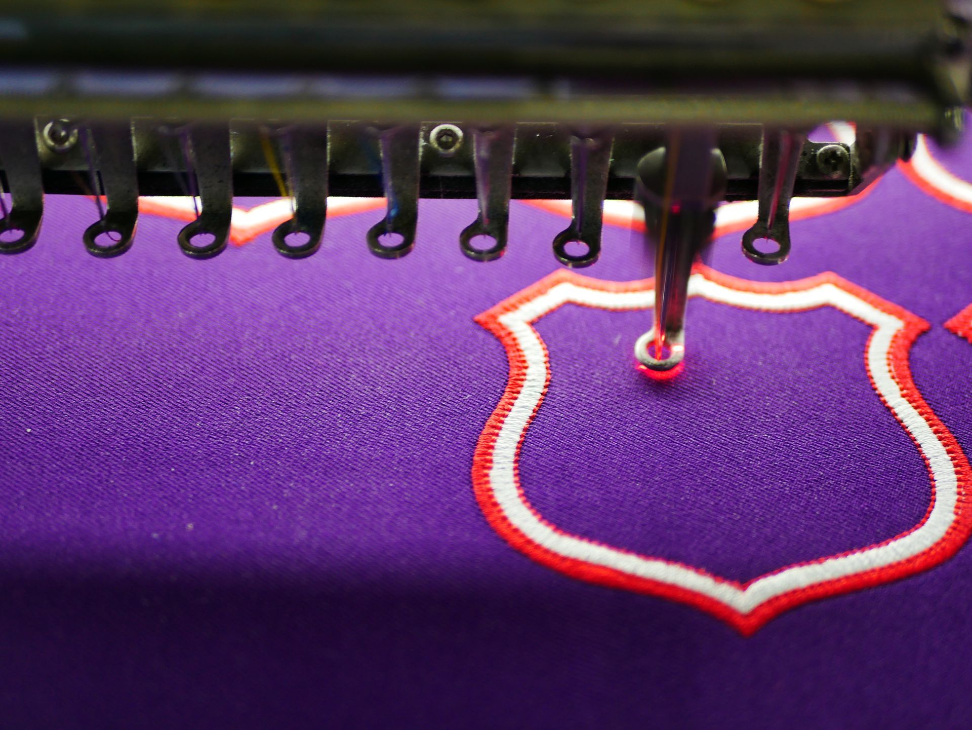 Person embroidering a blue floral design on a wooden hoop, surrounded by embroidery supplies.