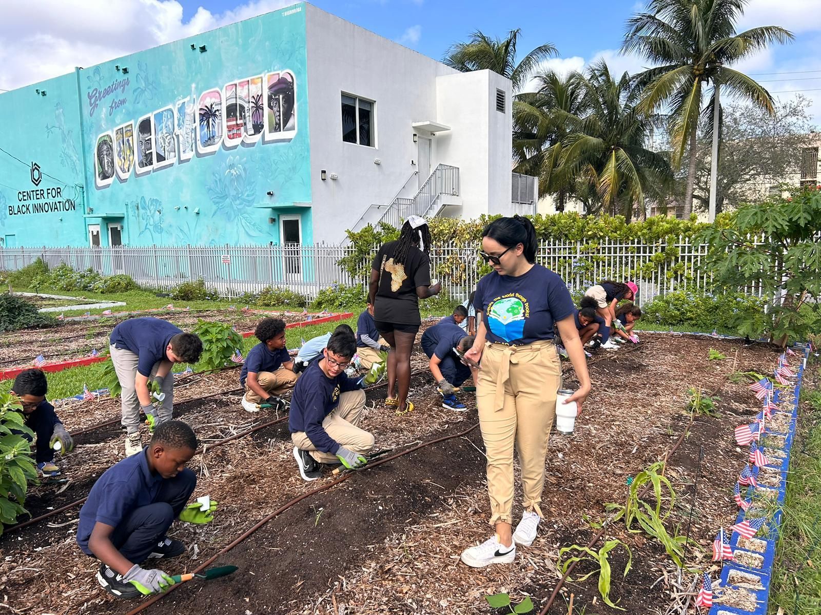 A group of people are working in a garden in front of a building.