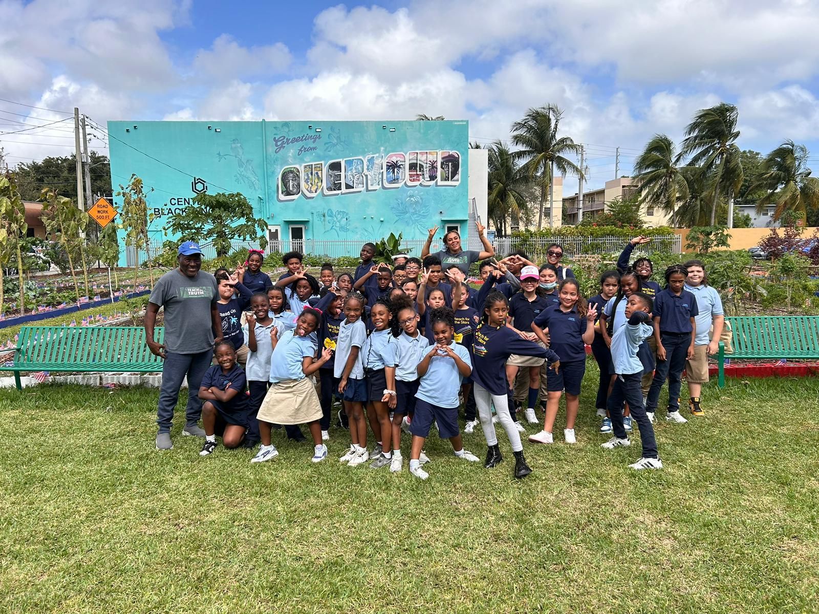 A group of children are posing for a picture in front of a blue building.