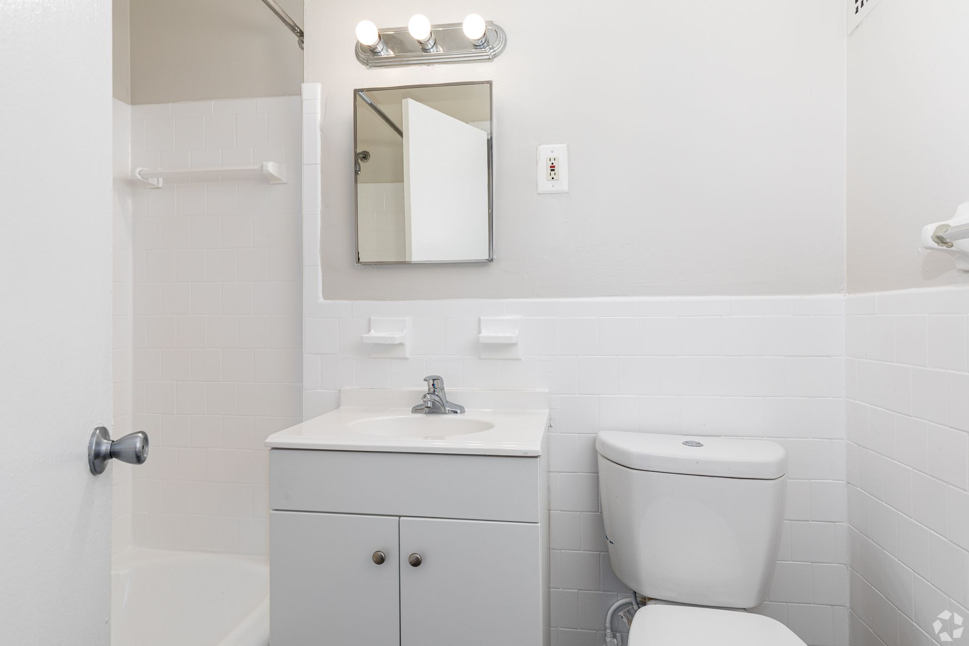 A bathroom with a toilet , sink , mirror and bathtub.