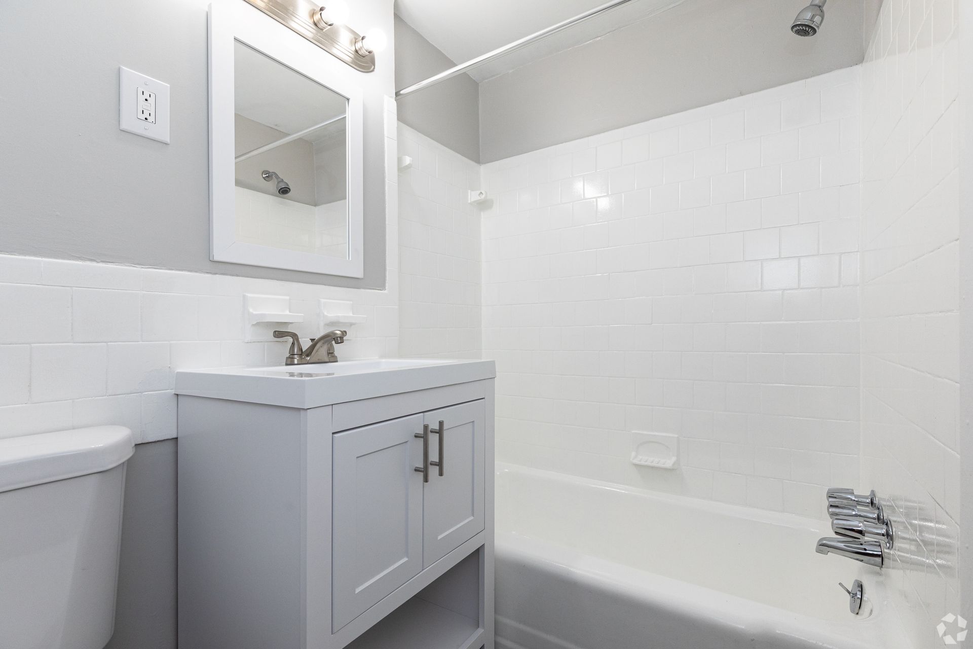 A bathroom with a sink , toilet , bathtub and mirror.