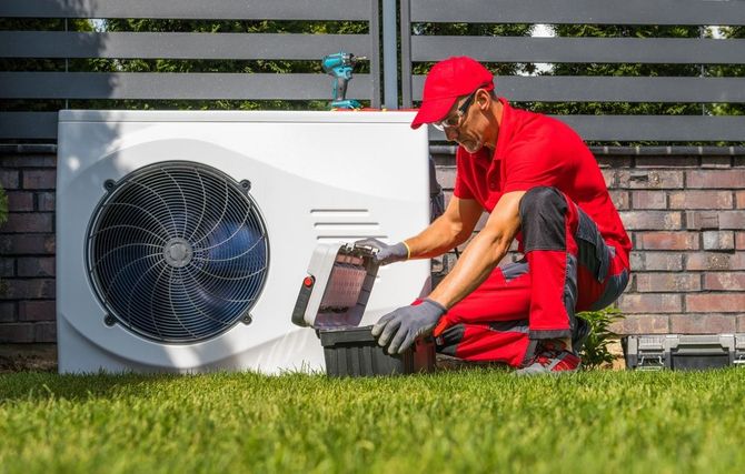 A man is working on a heat pump in a backyard.