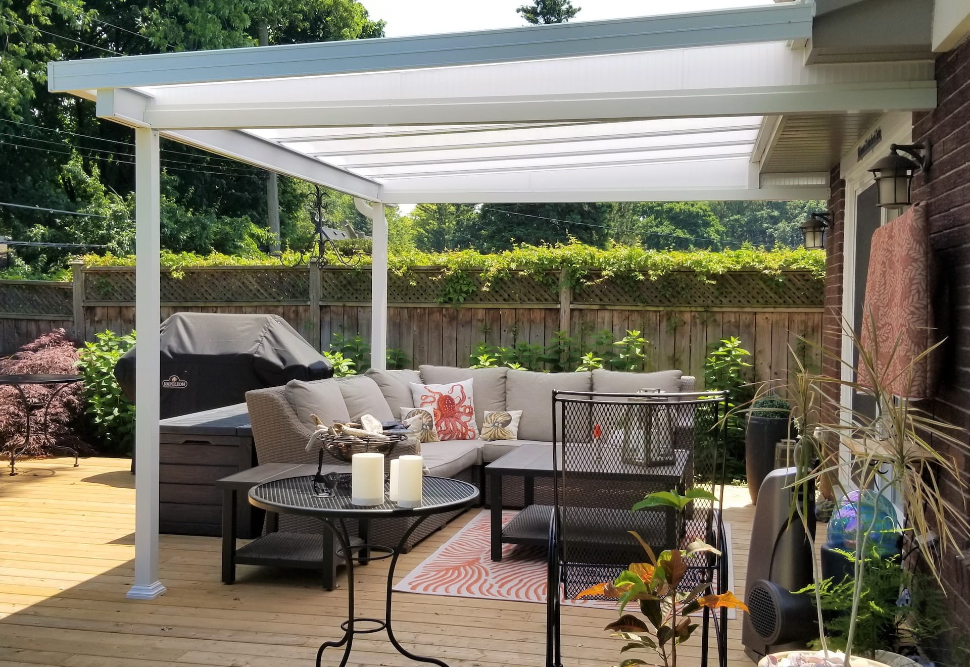A patio with a couch , table and chairs under a pergola.