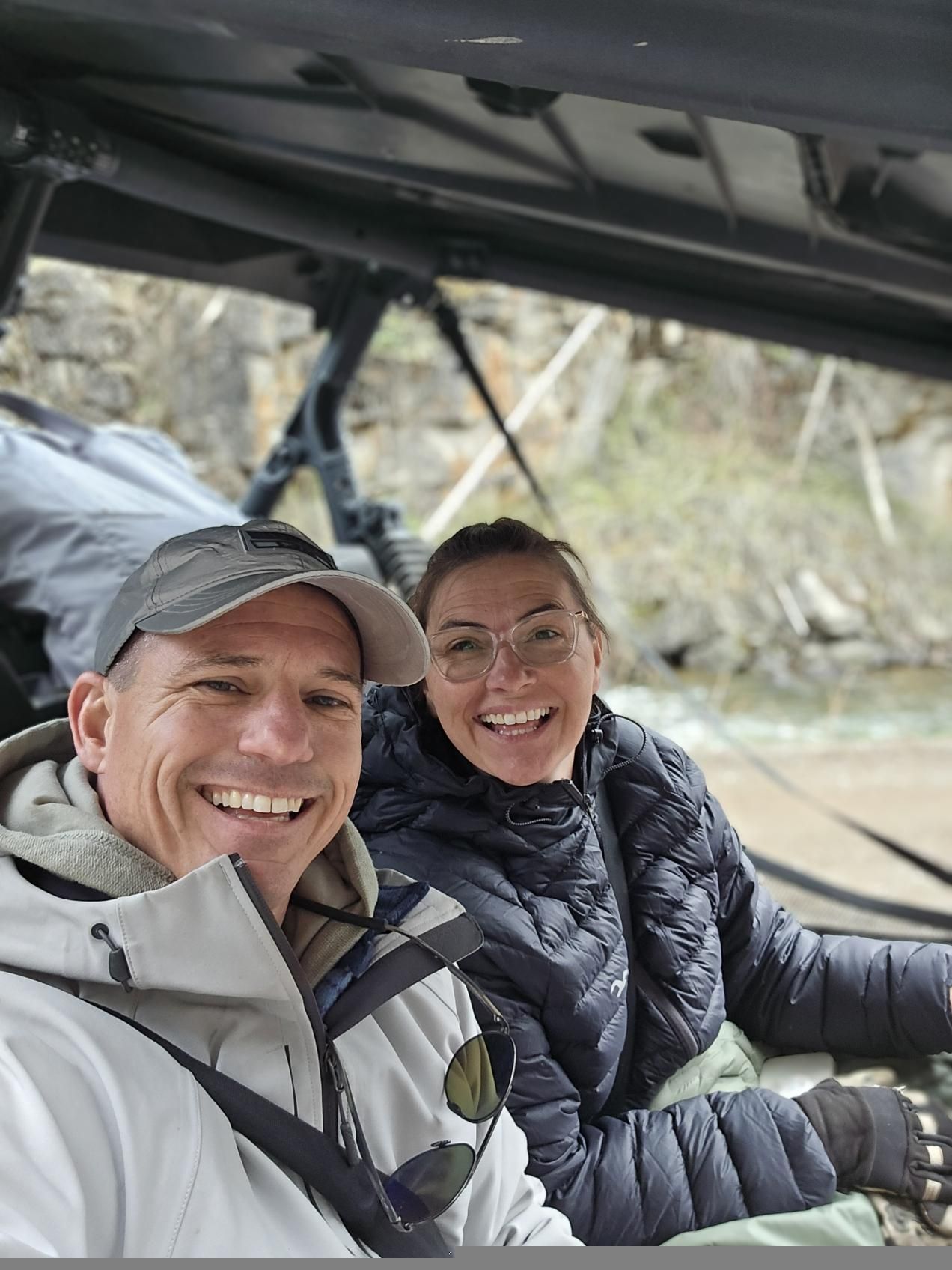 A man and a woman are sitting in a vehicle and smiling.