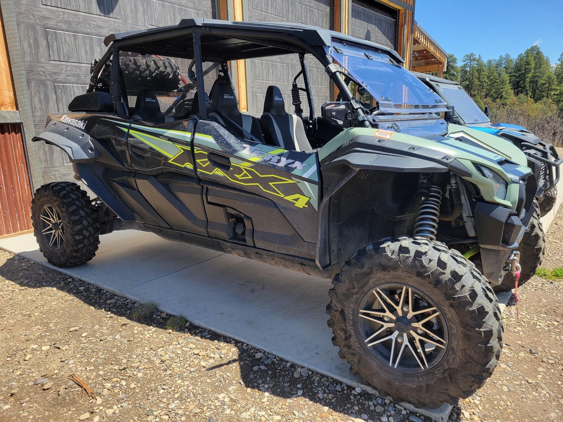 A green and black atv is parked on the side of a road.
