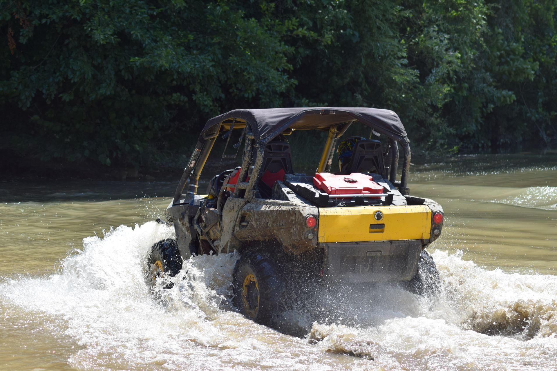 A black and yellow atv is driving through a river