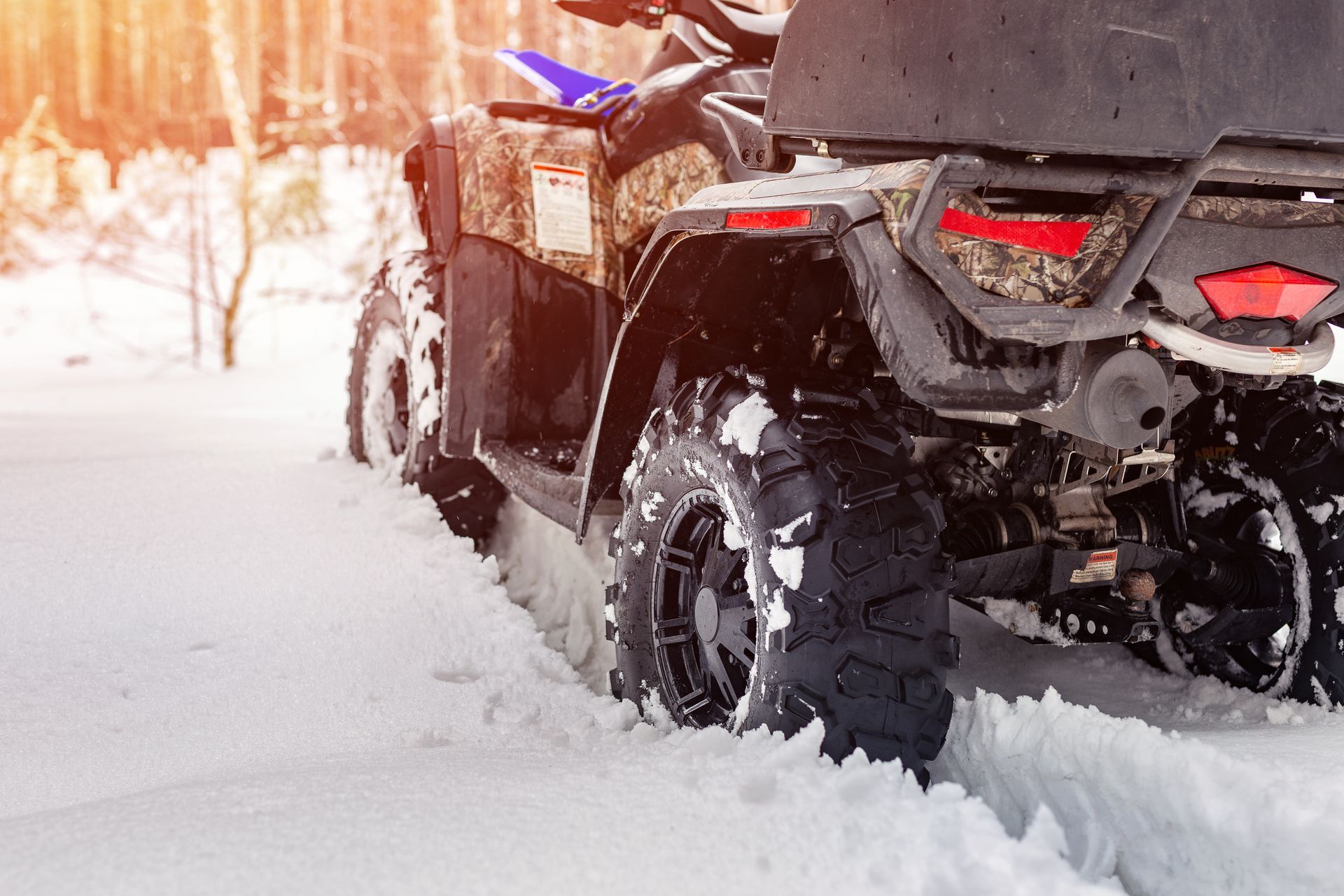 An atv is driving through the snow on a snowy road.