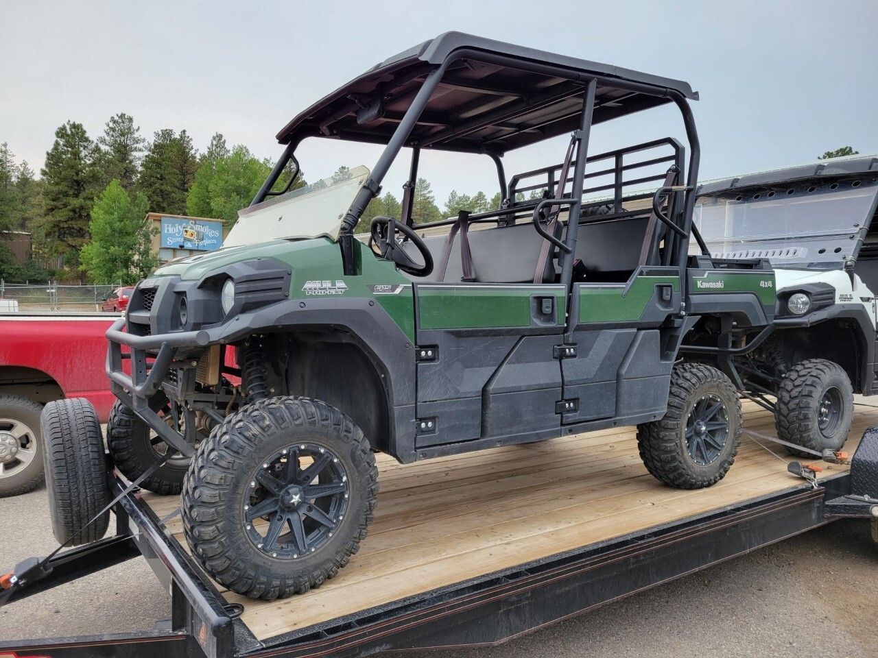 A green and black atv is sitting on top of a trailer.