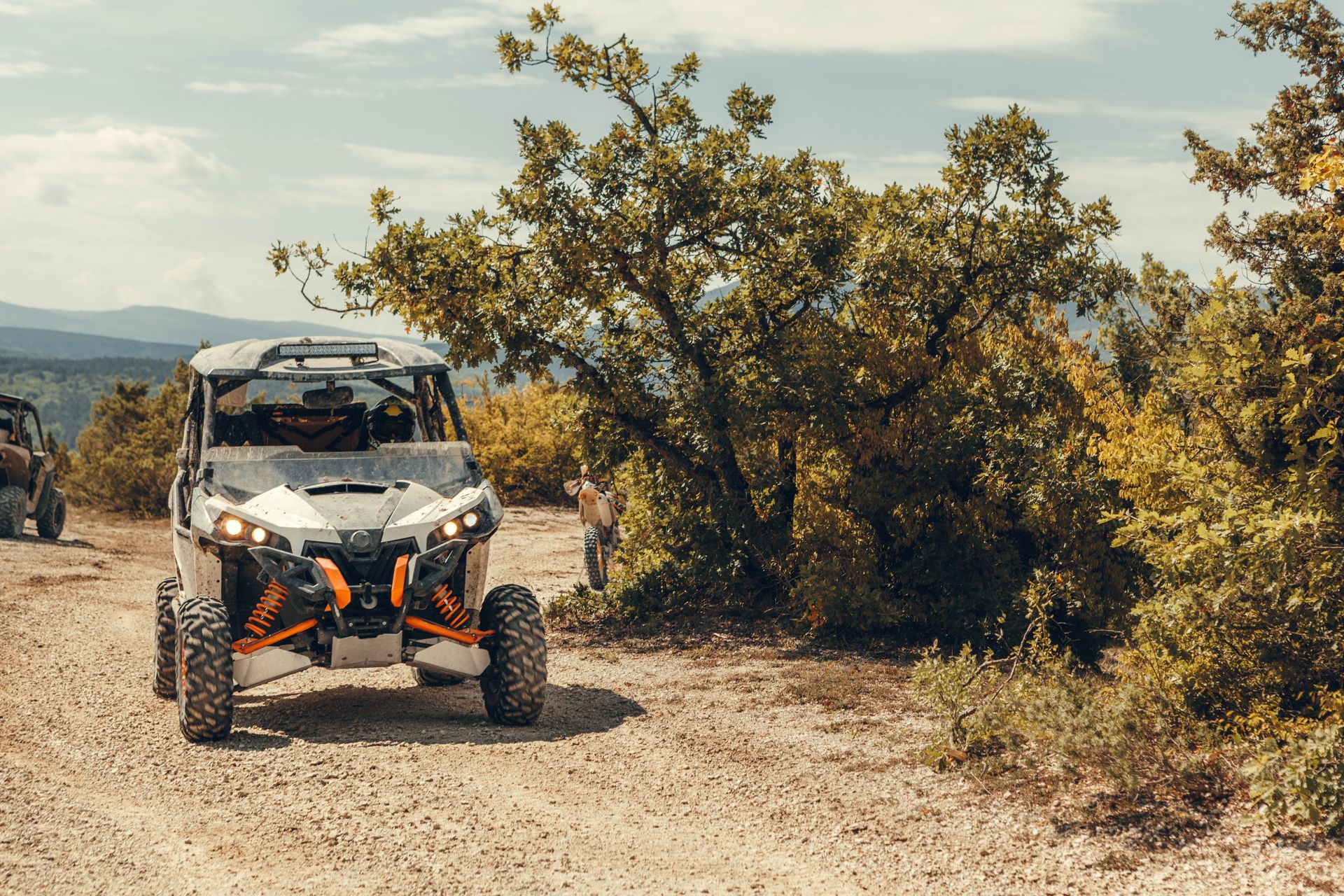 A couple of atvs are driving down a dirt road.