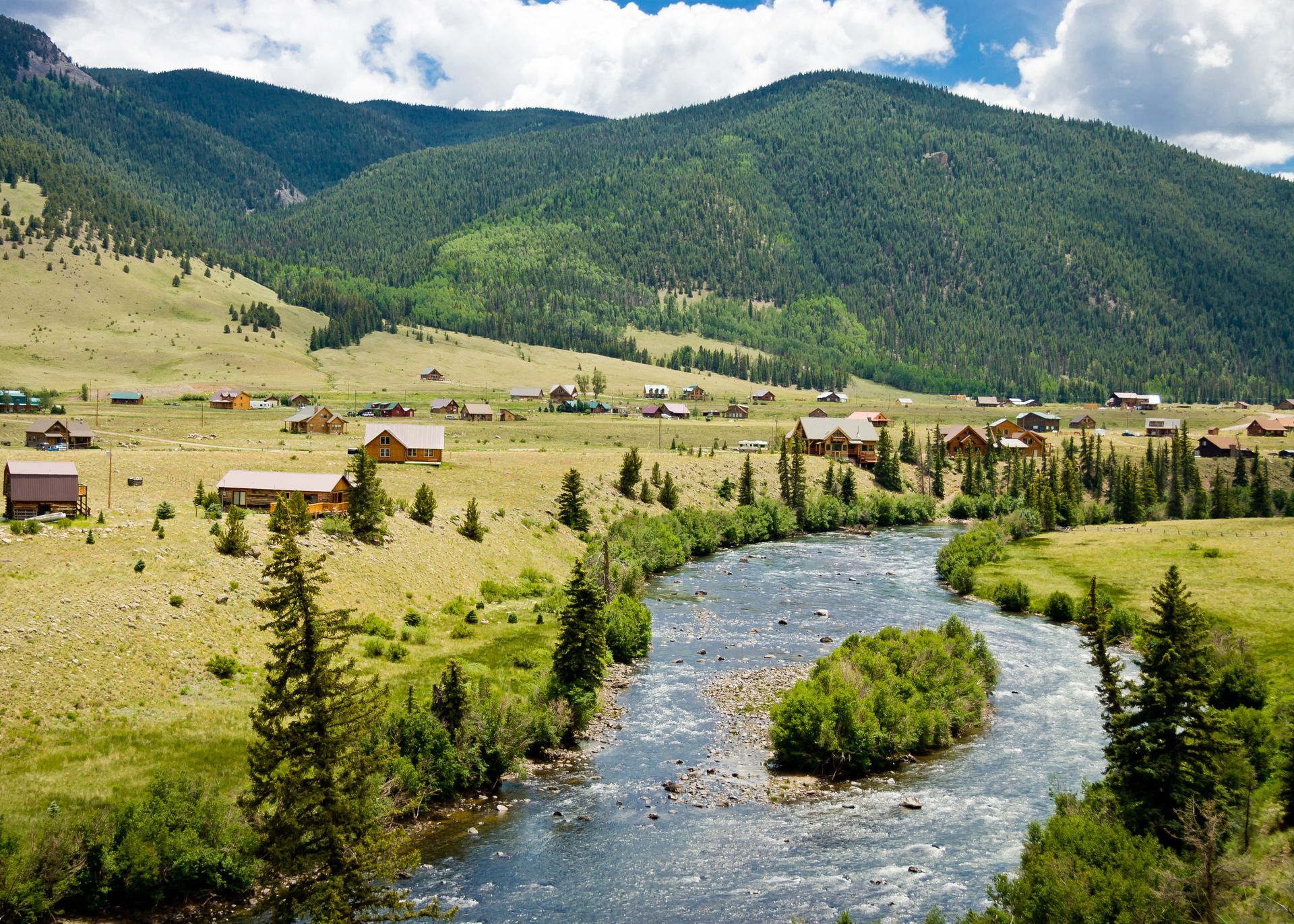 A river flowing through a valley with mountains in the background