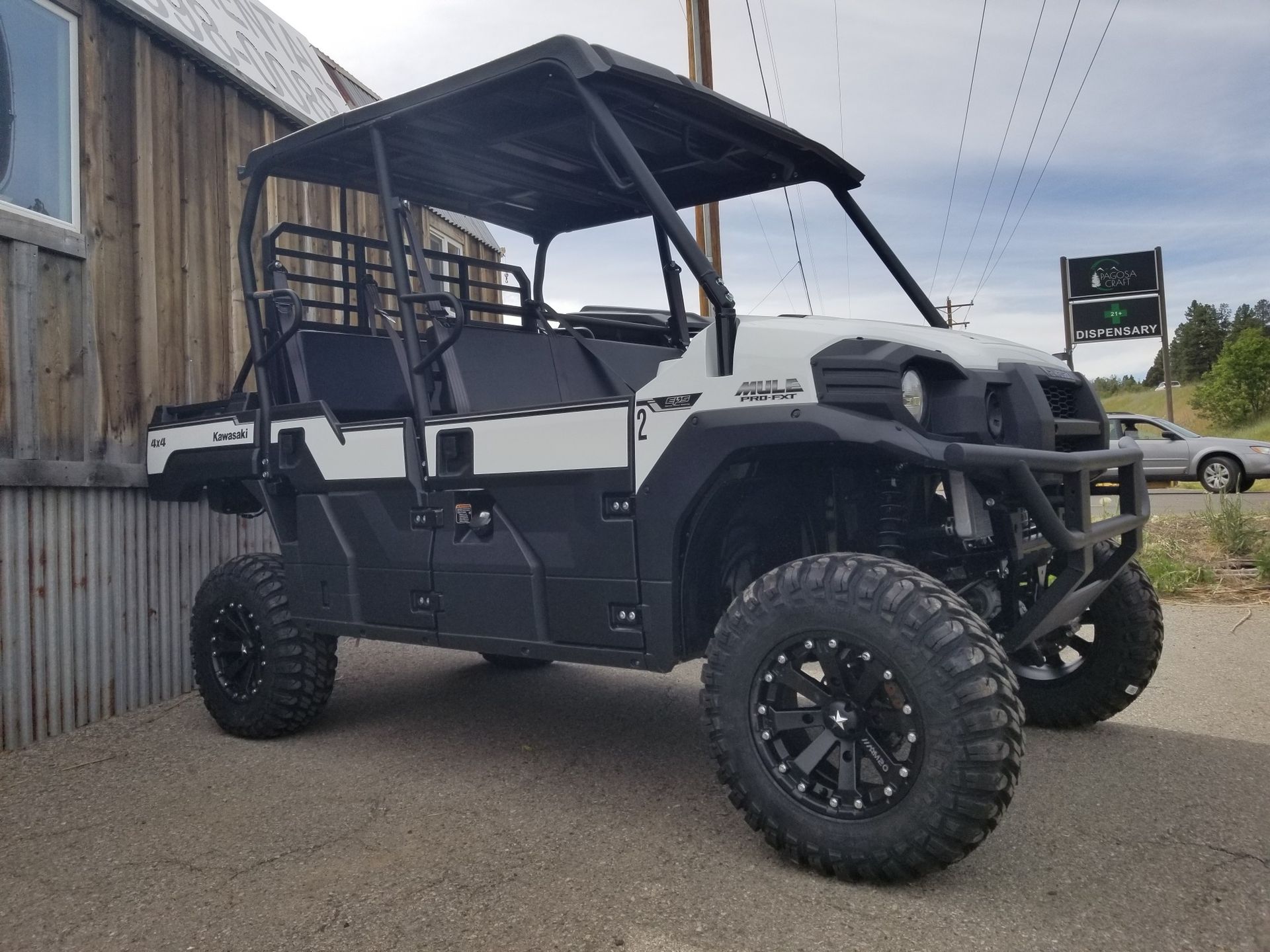 A white and black atv is parked in front of a wooden building.