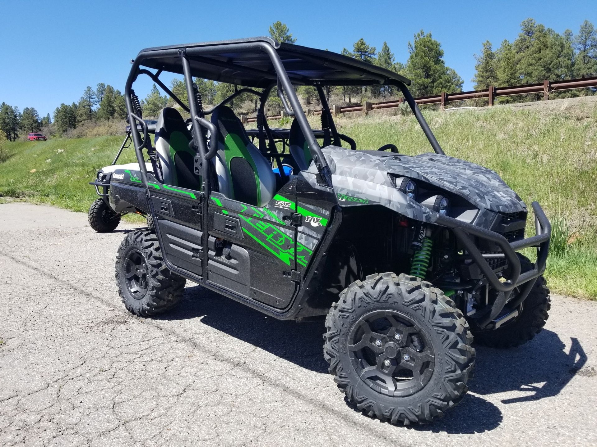 A green and black atv is parked on the side of a road.