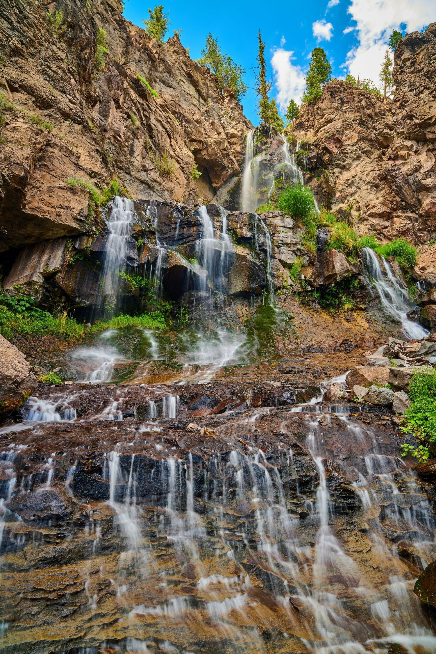 A waterfall is surrounded by rocks and trees in the middle of a forest.