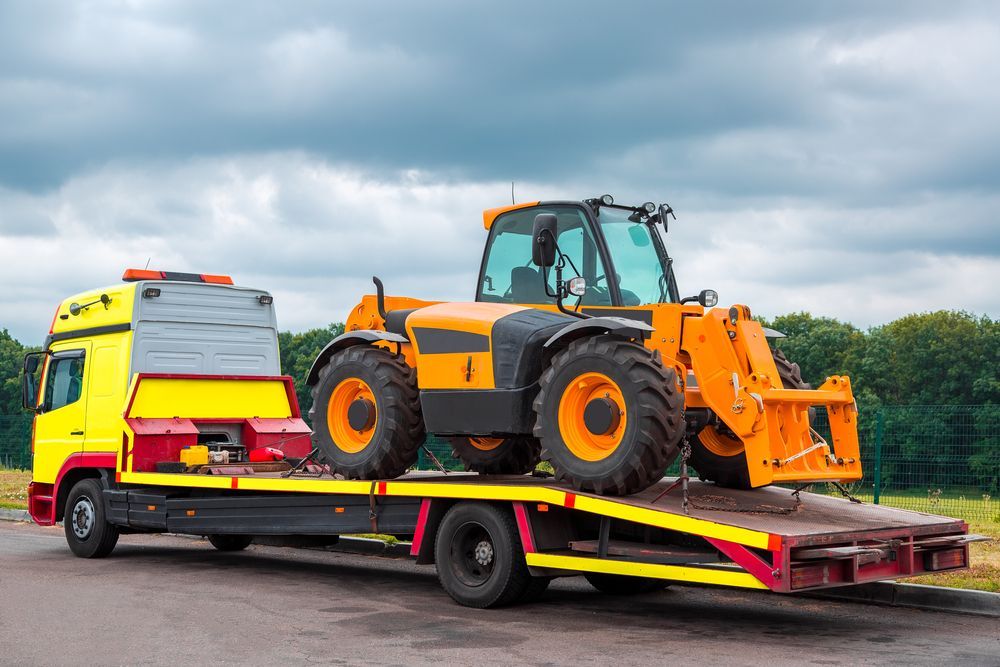 Orange Loader on a Red Flatbed Tow Truck Outdoors — Reliable Towing Services in Coffs Harbour, NSW