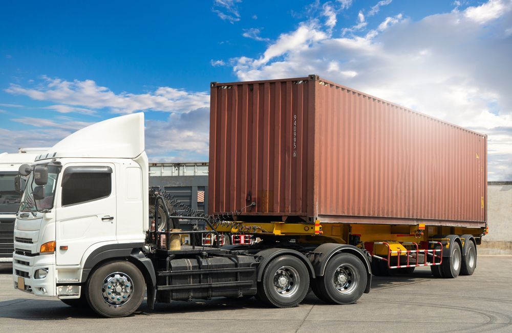 White Semi-truck Hauling a Red Shipping Container on a Highway — Reliable Towing Services in Coffs Harbour, NSW