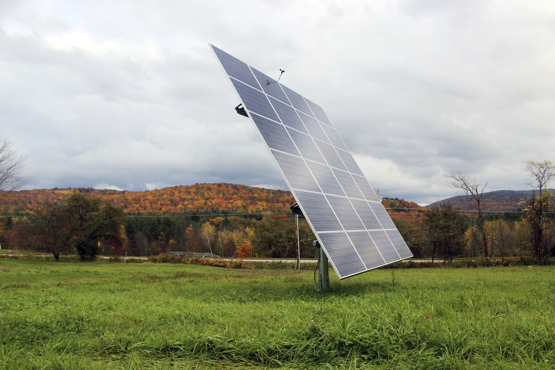 A large solar panel is sitting in the middle of a grassy field.