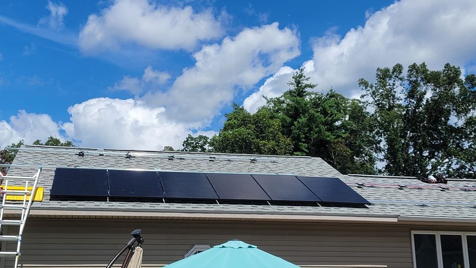 A house with solar panels on the roof and an umbrella in front of it.