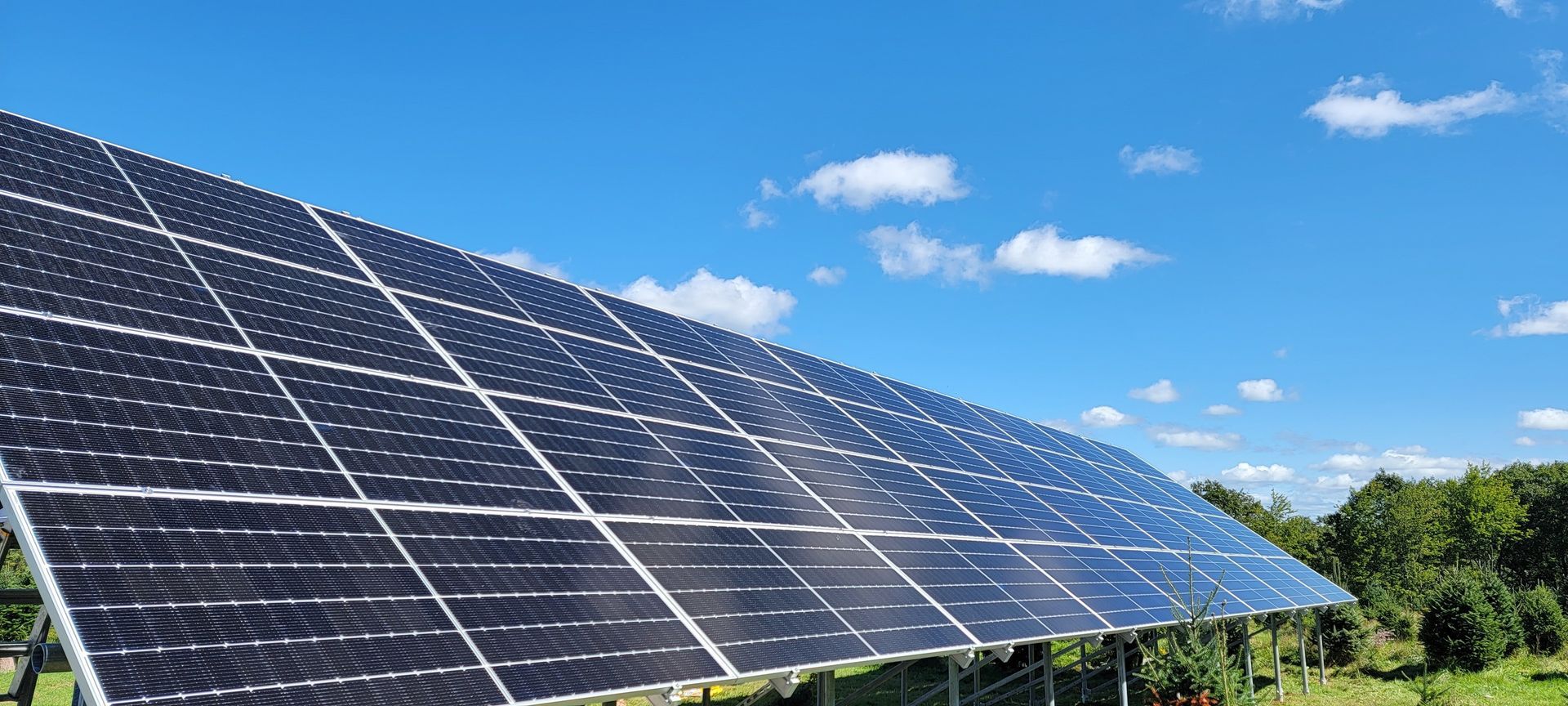 A row of solar panels in a field with a blue sky in the background.