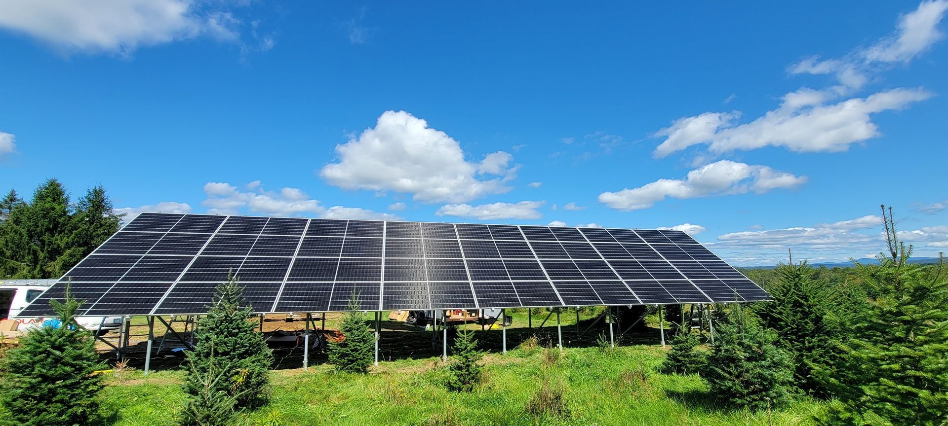 A large solar panel is sitting in the middle of a grassy field.