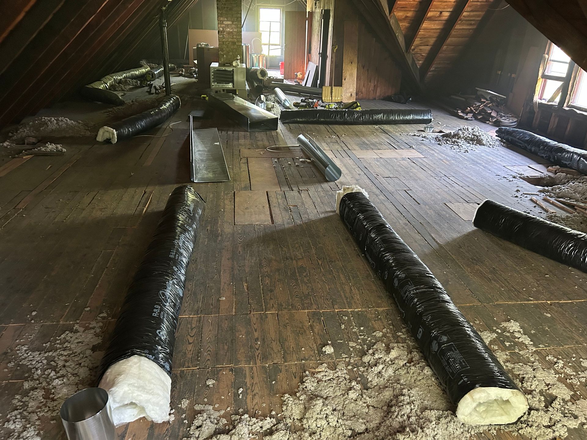 Attic with wooden floor; HVAC ducts and insulation are installed.