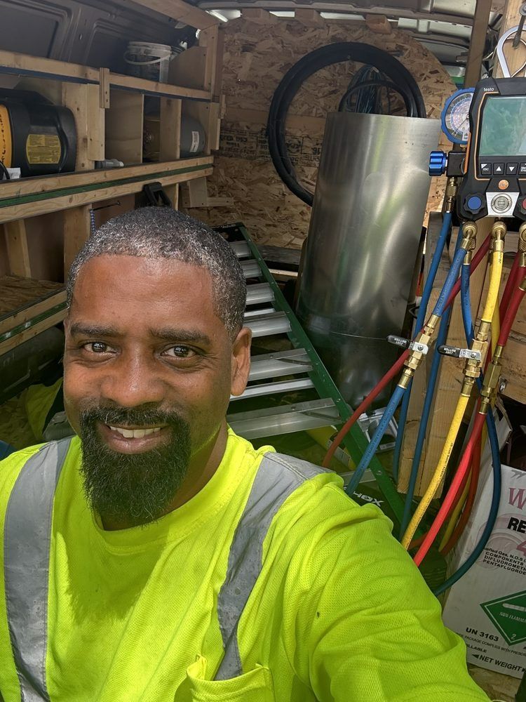 Man in neon shirt smiles, standing in a utility van with equipment.