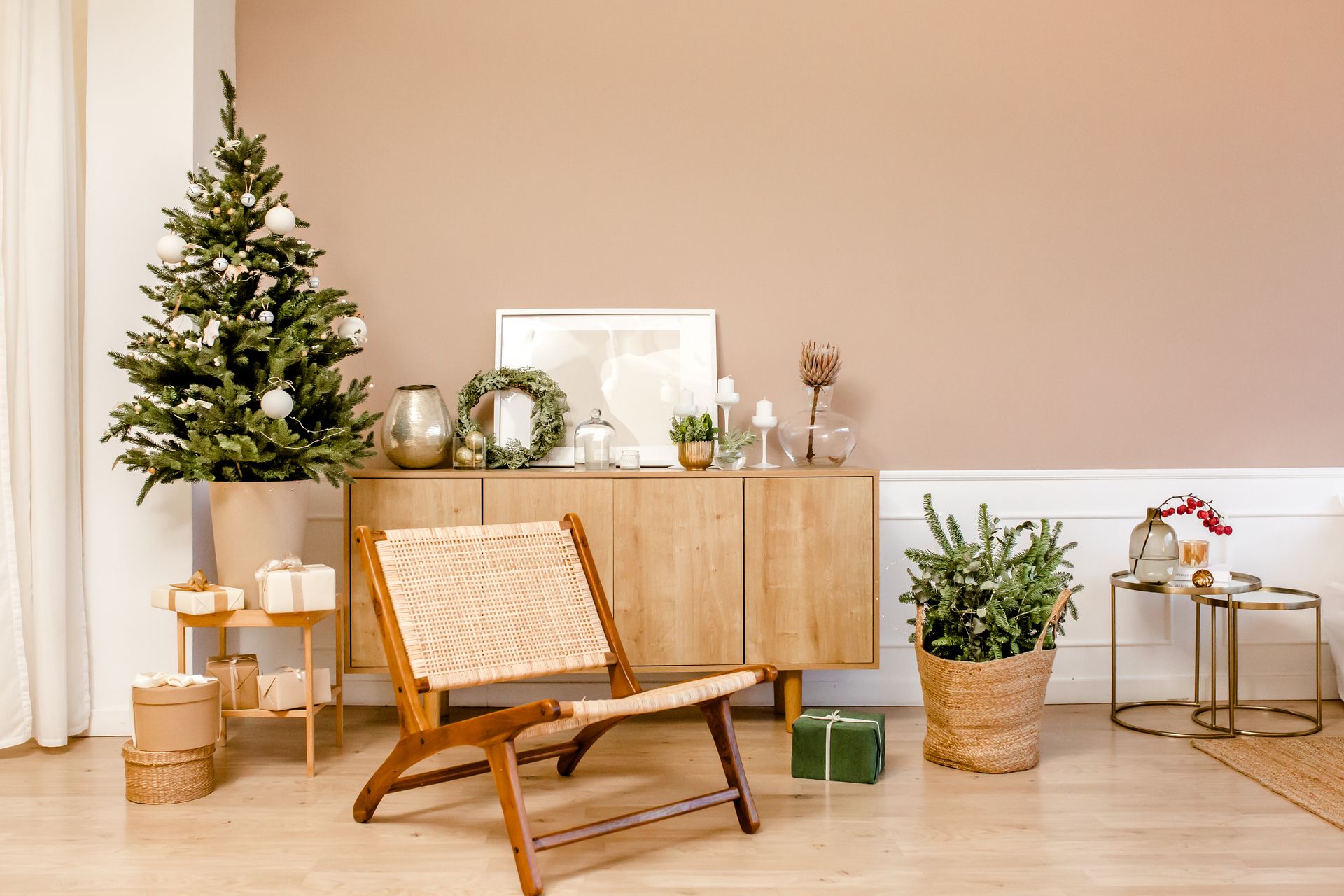 Living room with Christmas decorations: tree, presents, chair, and cabinet against a peach wall.