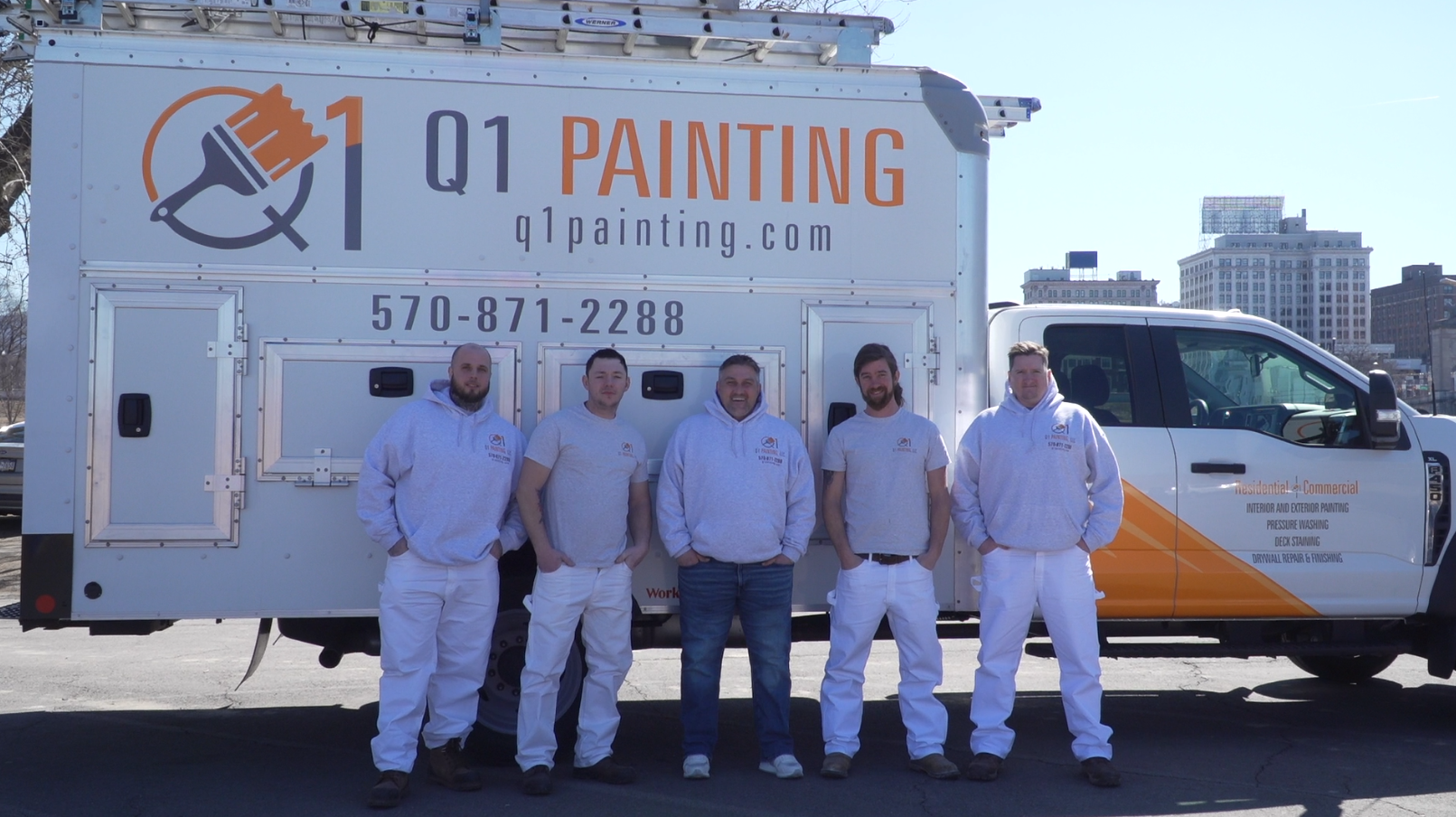A group of men are standing in front of a painting truck.