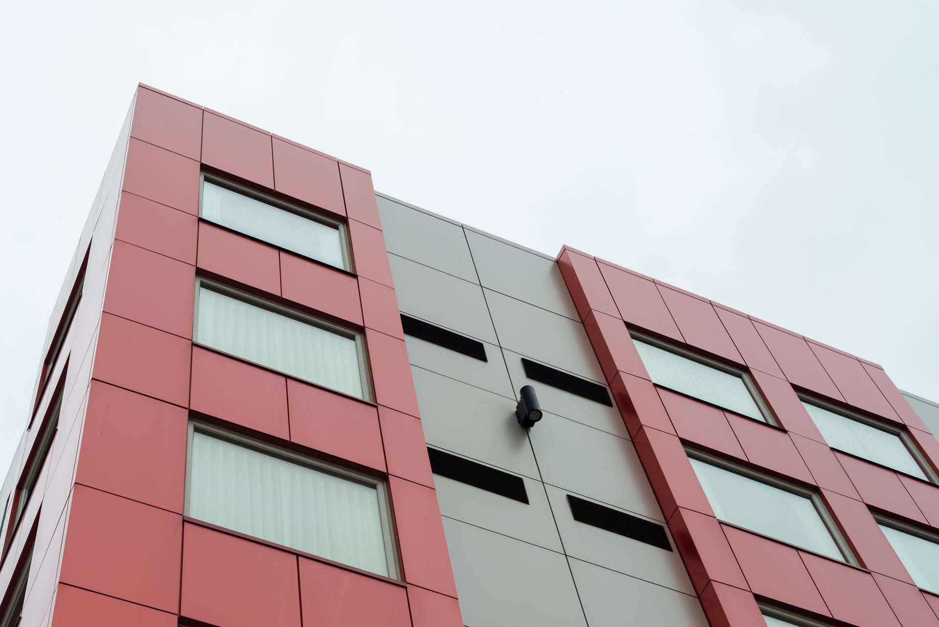 A red and grey building with a clock on the side