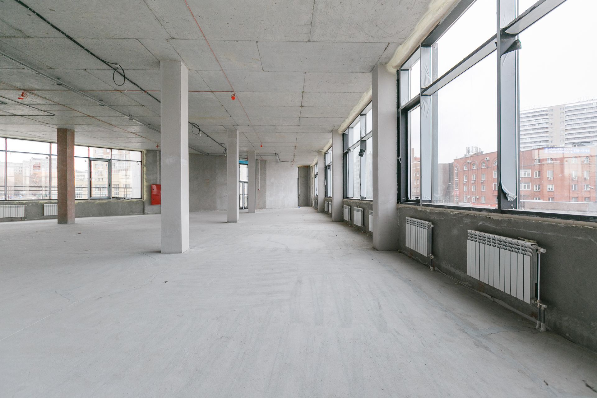 A large empty room with a lot of windows and radiators.