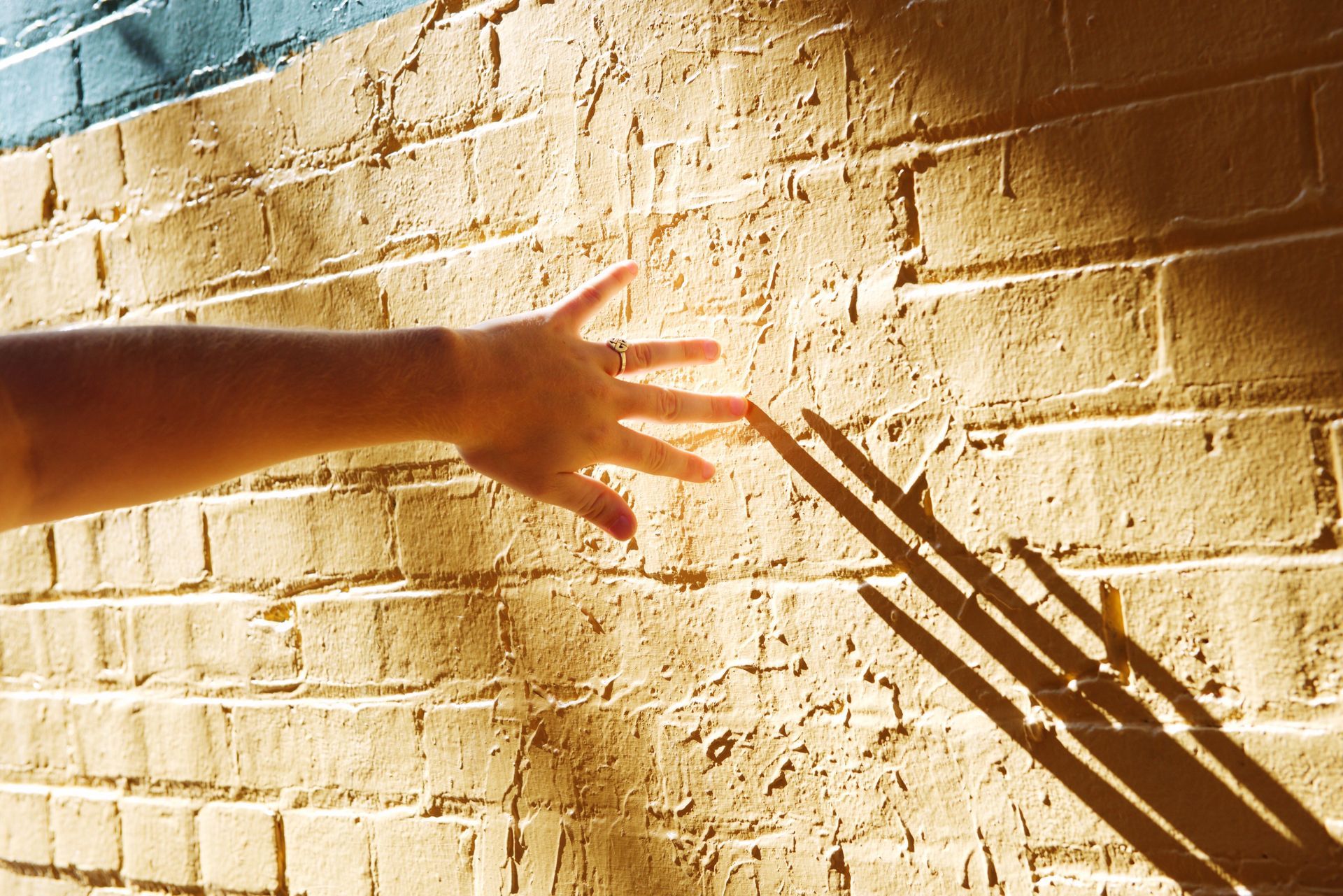 A person 's hand is reaching out towards a brick wall
