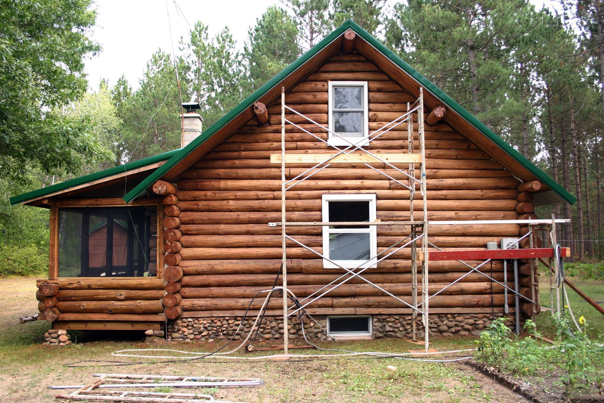 A log cabin with a green roof and scaffolding around it