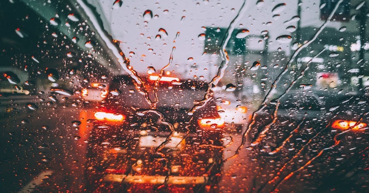 A car is driving down a wet street in the rain.