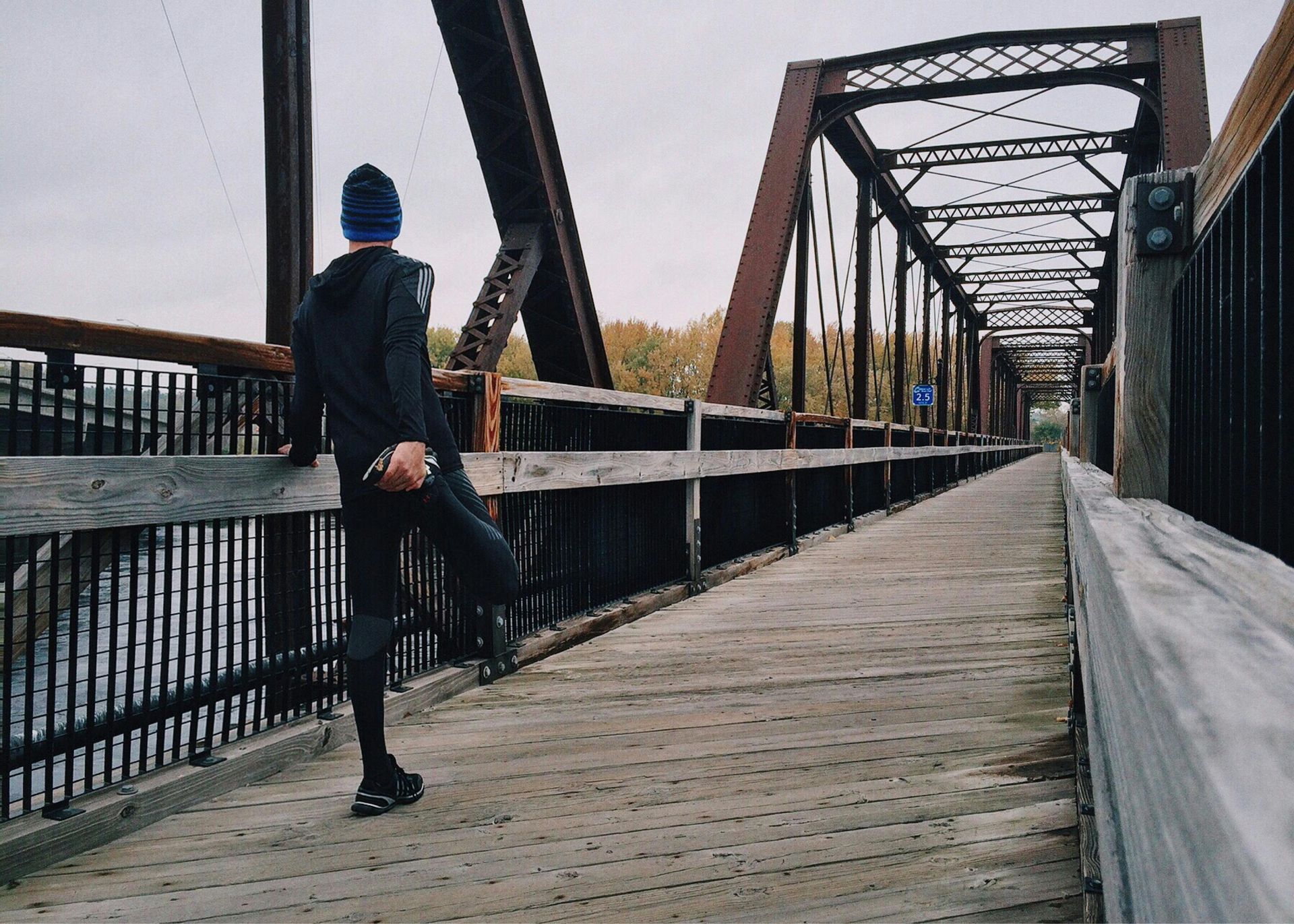 A person is stretching their legs on a bridge.