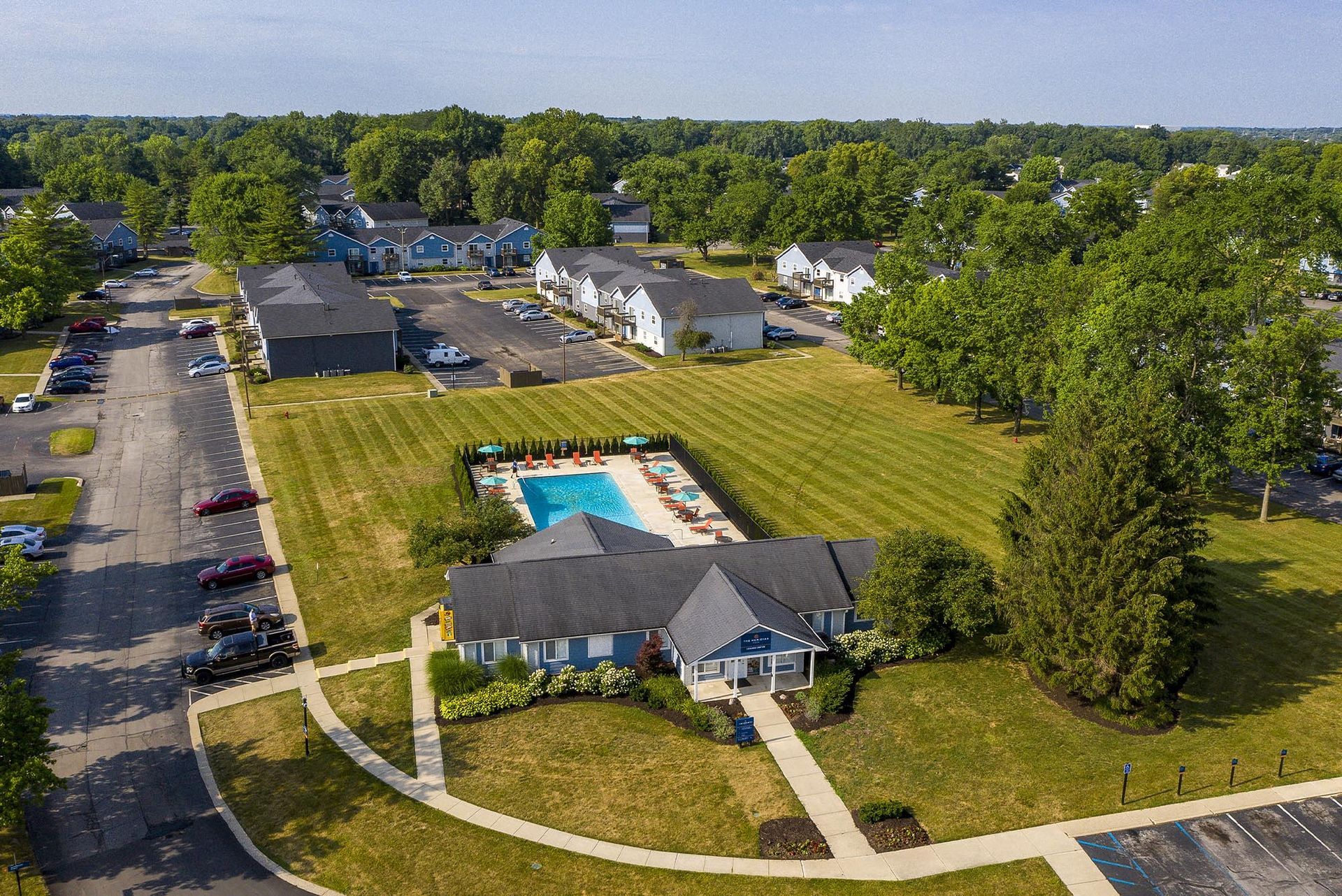 Aerial view of an apartment community showing a central pool, clubhouse, and surrounding parking.