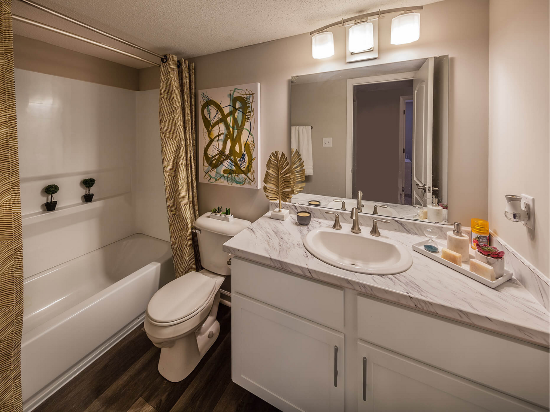 Bathroom in an apartment with marble vanity, single sink, large mirror, and tub/shower.