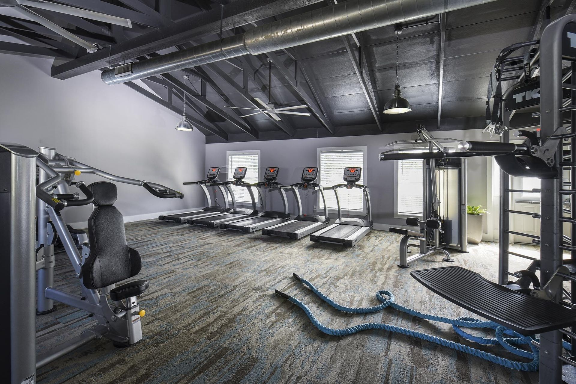 Indoor fitness center with treadmills and weight machines in an industrial-style gym.