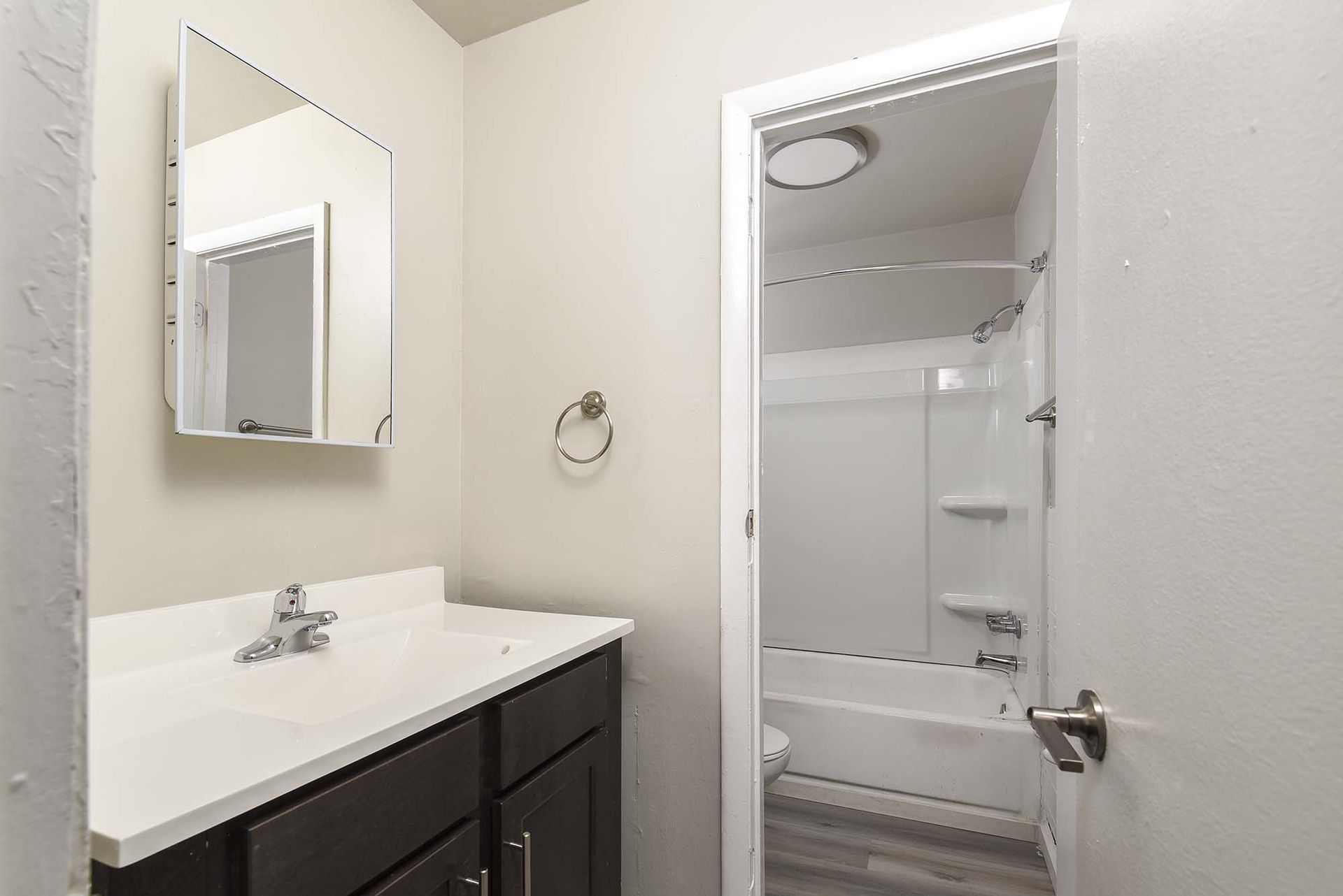 Bathroom with dark vanity, white countertop, mirror, and a shower/bathtub.