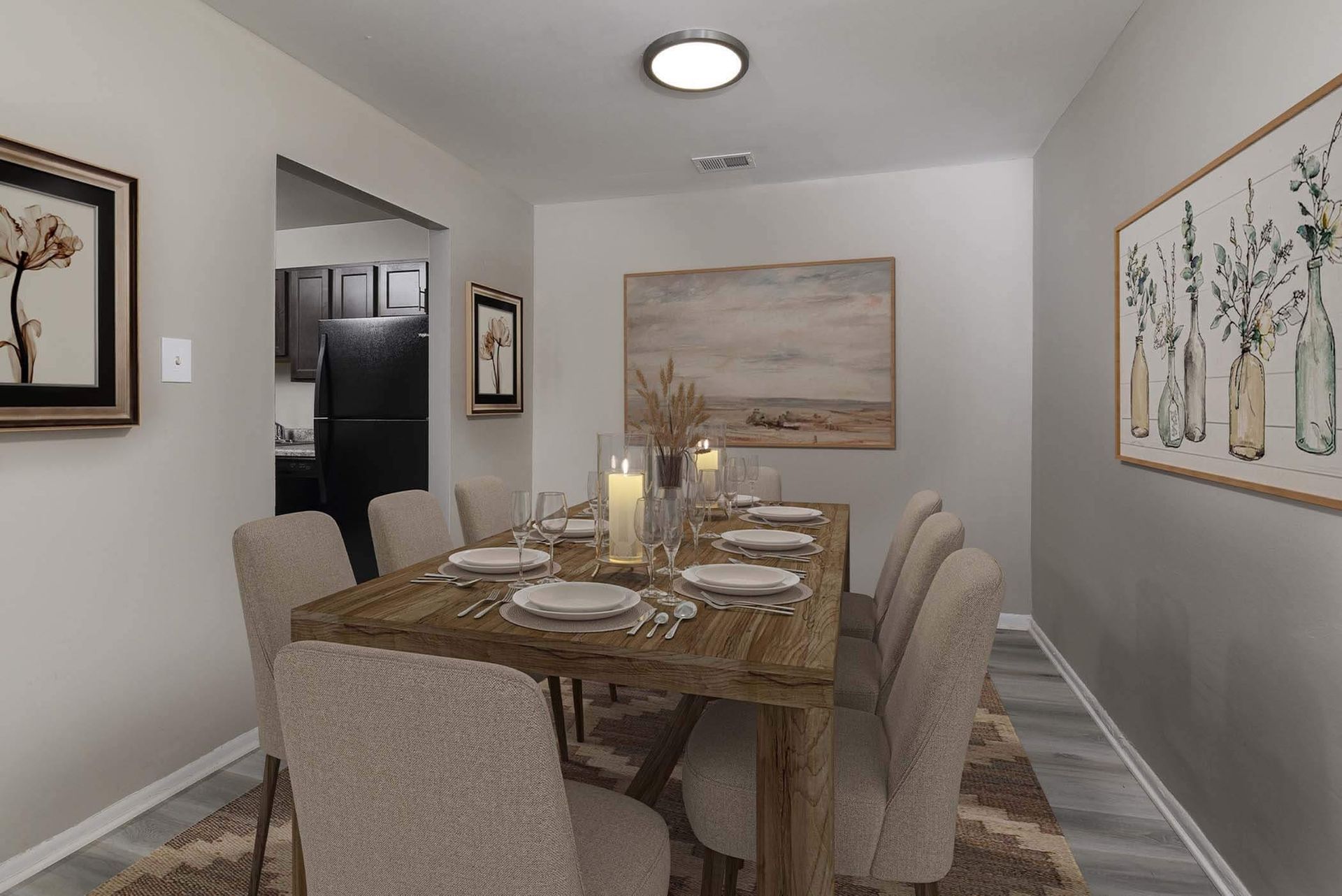 Dining room in an apartment with a wooden table, beige chairs, and wall art.