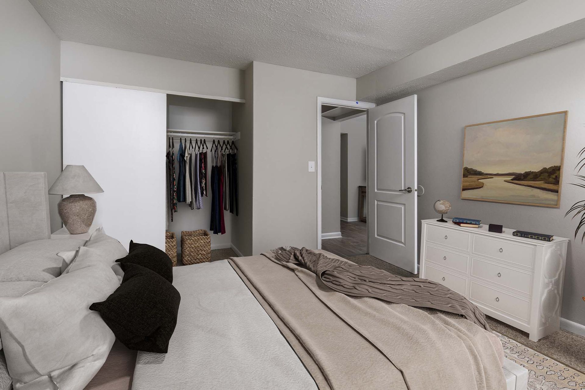Bedroom with bed, dresser, and open closet in an apartment.