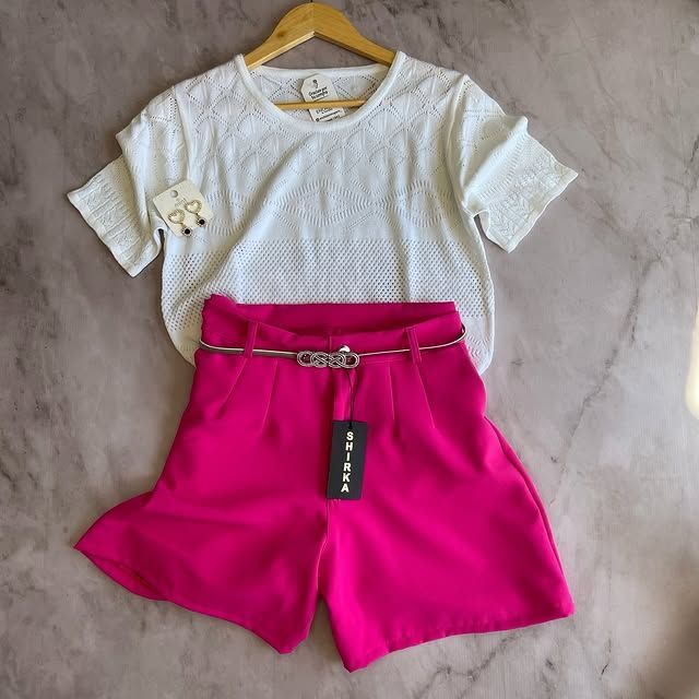Top de ojales blanco y short fucsia de tiro alto con cinturón plateado.