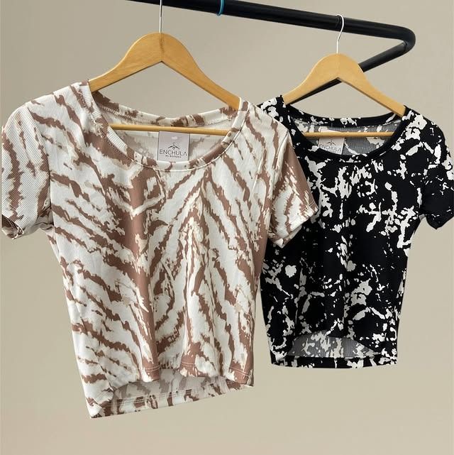 Dos tops cortos con efecto tie-dye, uno marrón y blanco, y otro blanco y negro, colgados en un perchero.