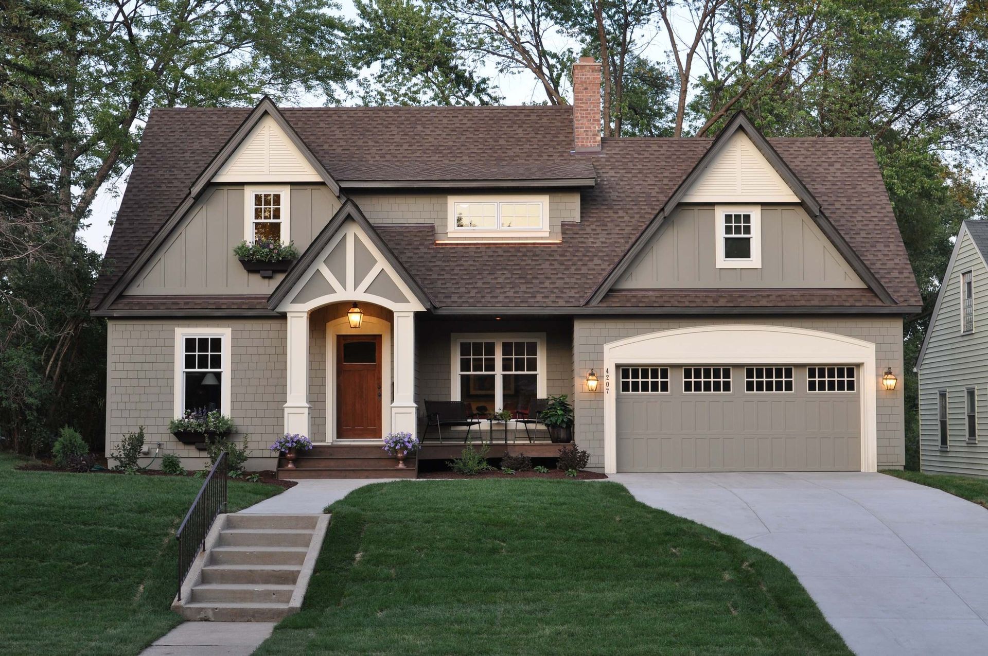 Two-story home with light green siding, brown roof, and concrete driveway.